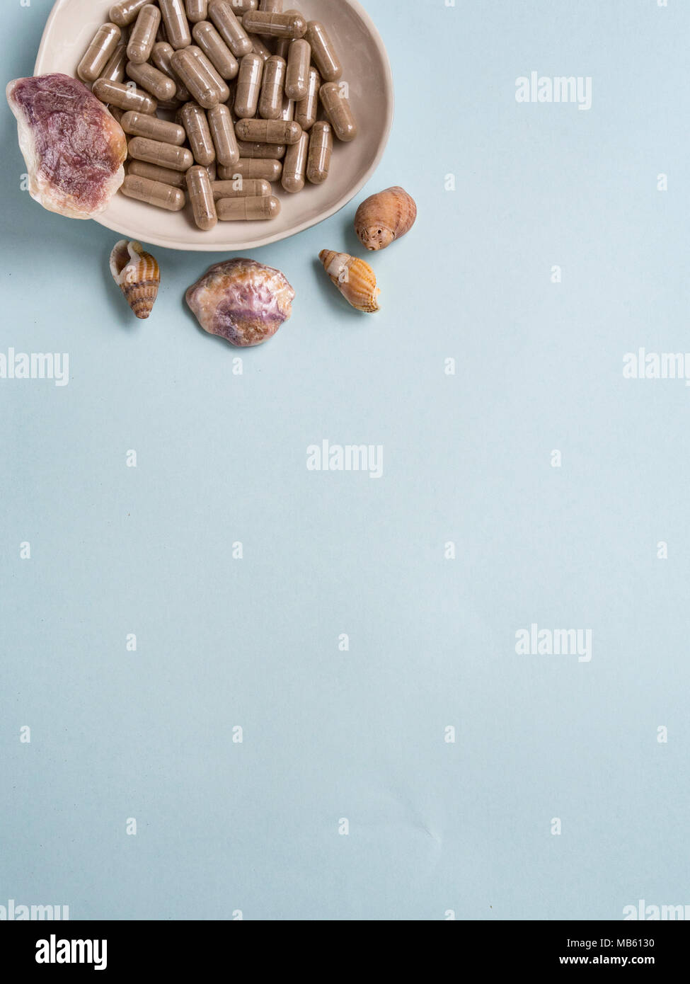 Capsule pills with seashells on blue background Stock Photo - Alamy