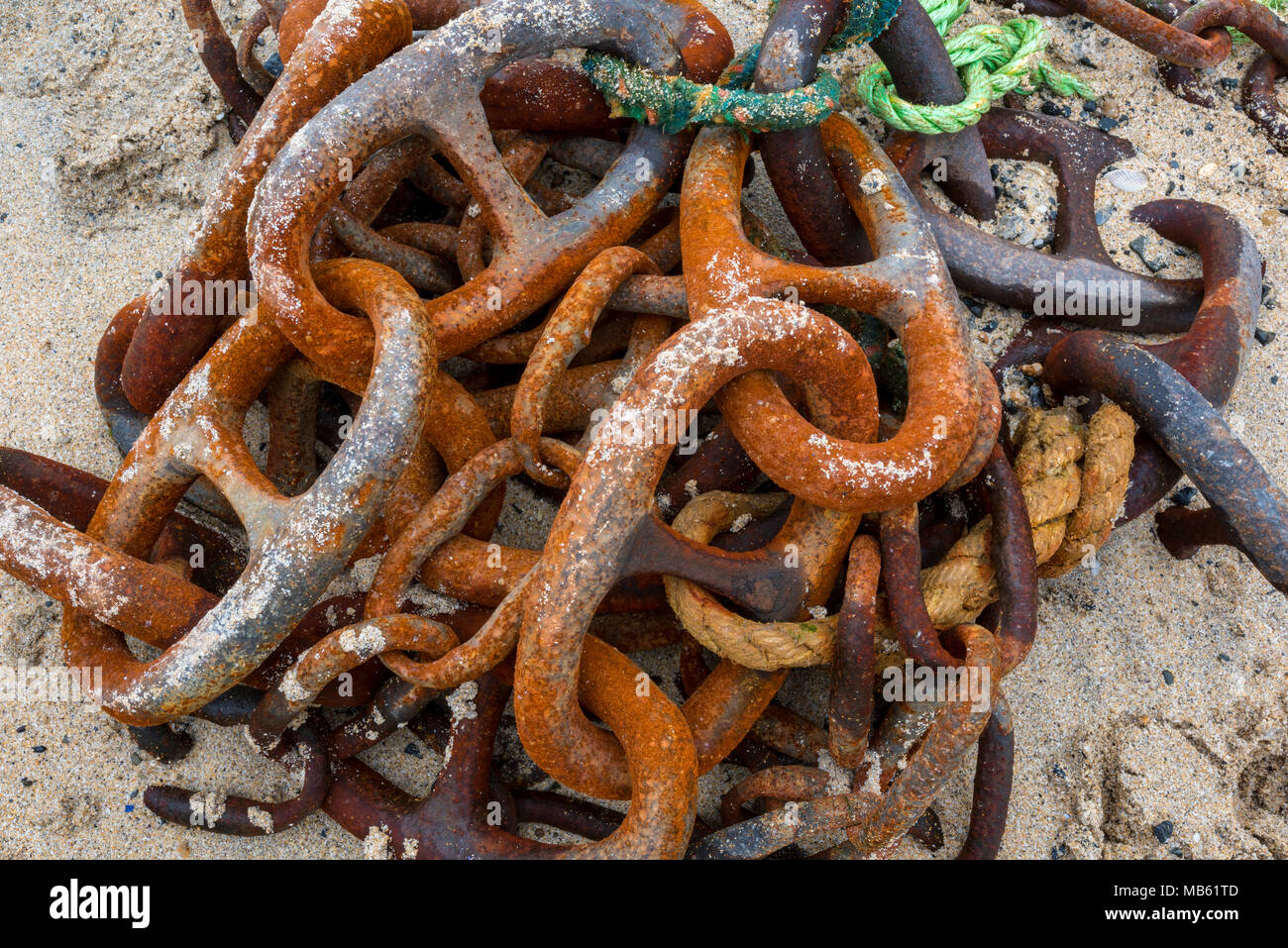 An old rusty corroded anchor chain with a lungless joining shackle discarded and laying on a sandy beach. Anchoring cable lying on the shore with rust Stock Photo