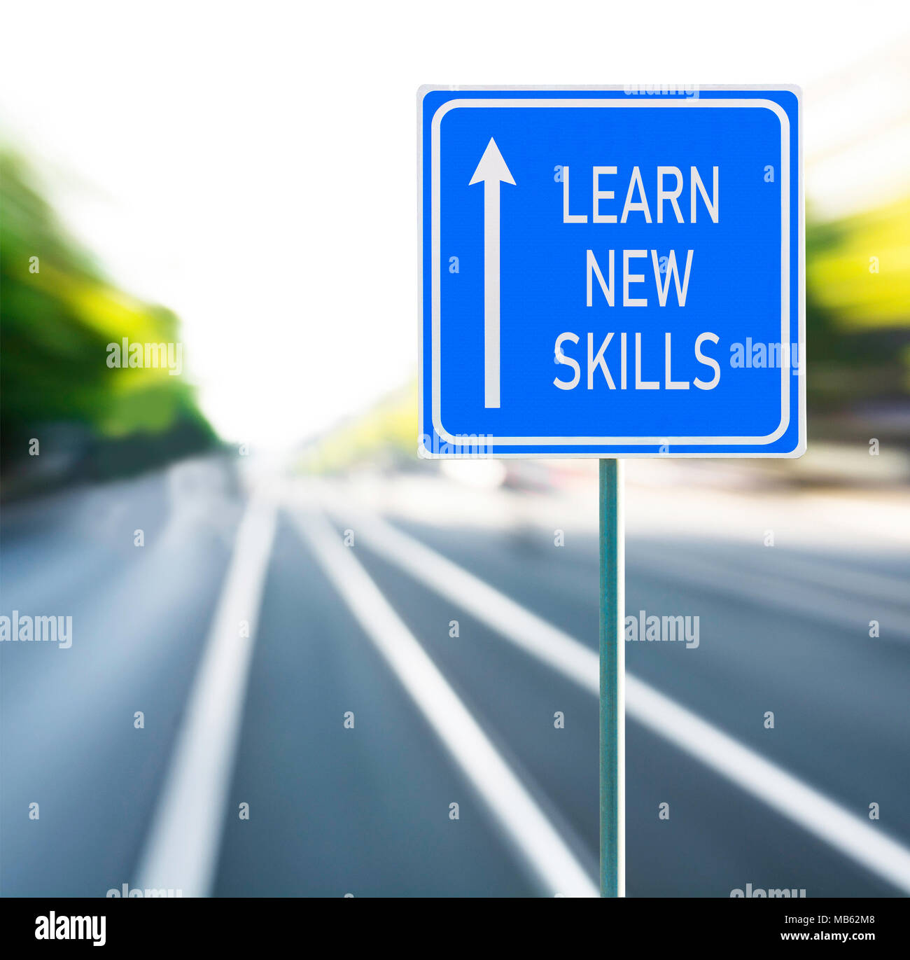 Learn new skills motivational phrase on blue road sign with arrow and blurred speedy background. Copy space. Stock Photo