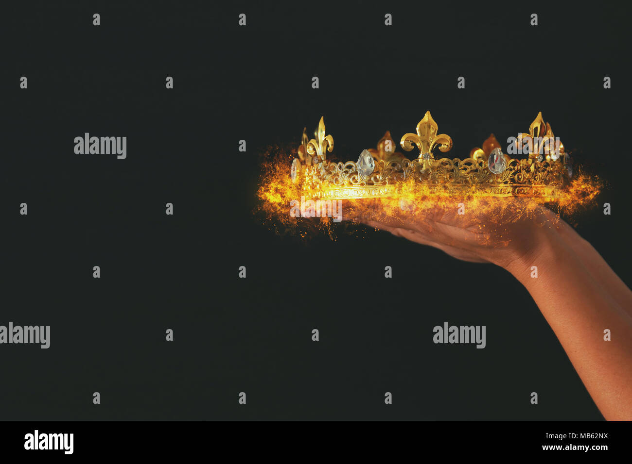 Woman's hand holding a burning crown over black background Stock Photo ...