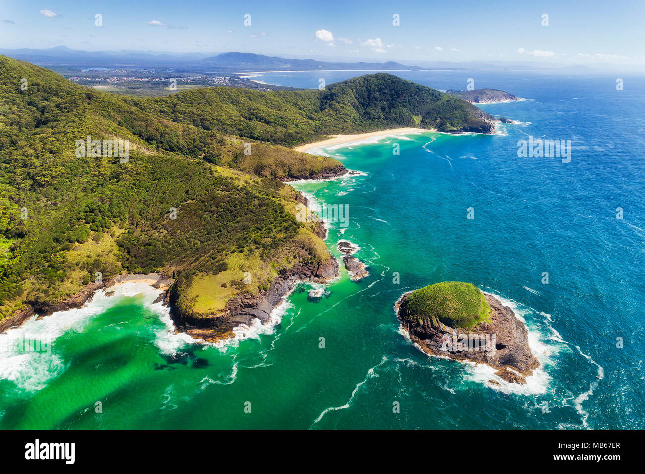 Scenic aerial view of colourful Australian pacific coast off Arakoon national park with tall hills cutting down to cliffy shore and beaches. Stock Photo