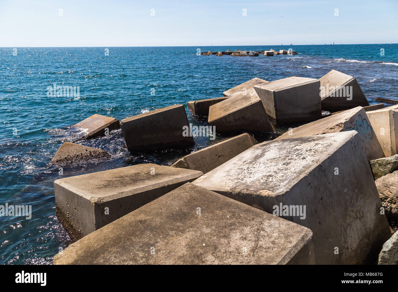 Cubic blocks of concrete form a breakwater on the beach of Nova Icaria