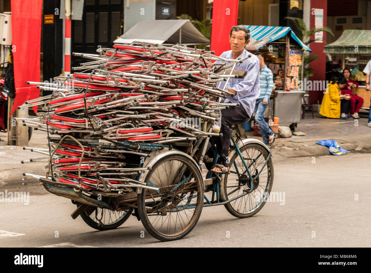 Man on cycle rickshaw delivering portable seats in Da Nang Vietnam Stock Photo
