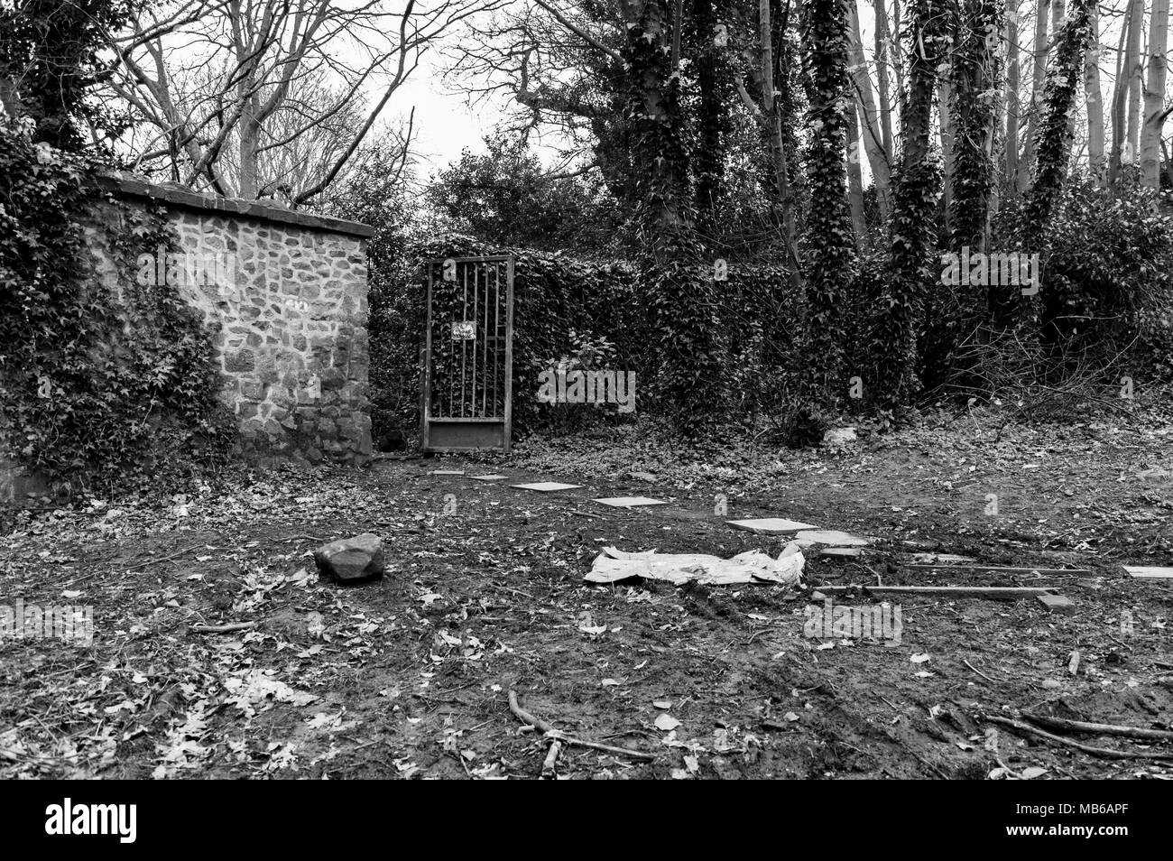 Side entrance to London Road Cemetery, over grown with open iron gate Stock Photo