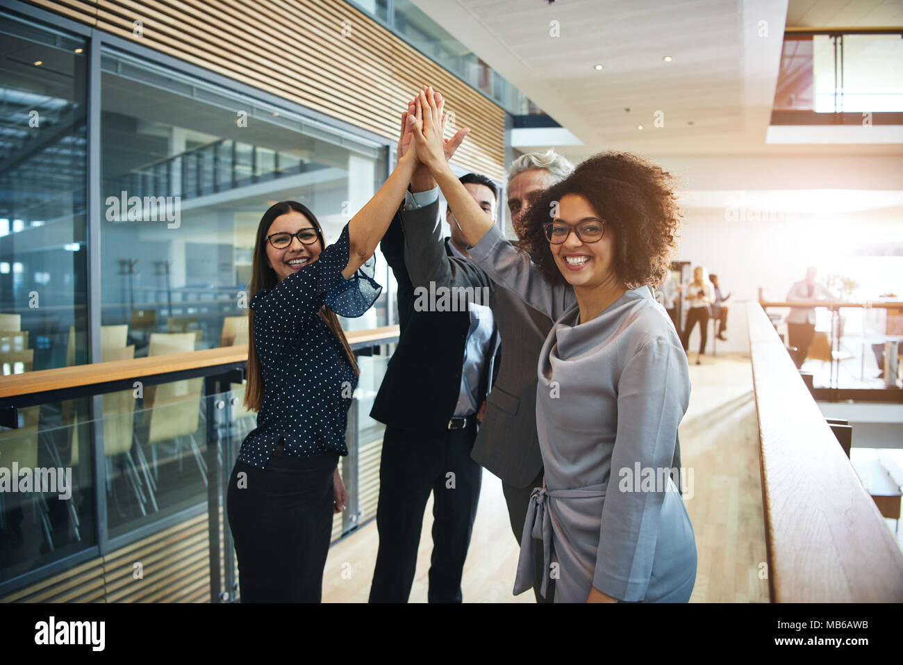 Smiling black and white team standing and giving high five cheering