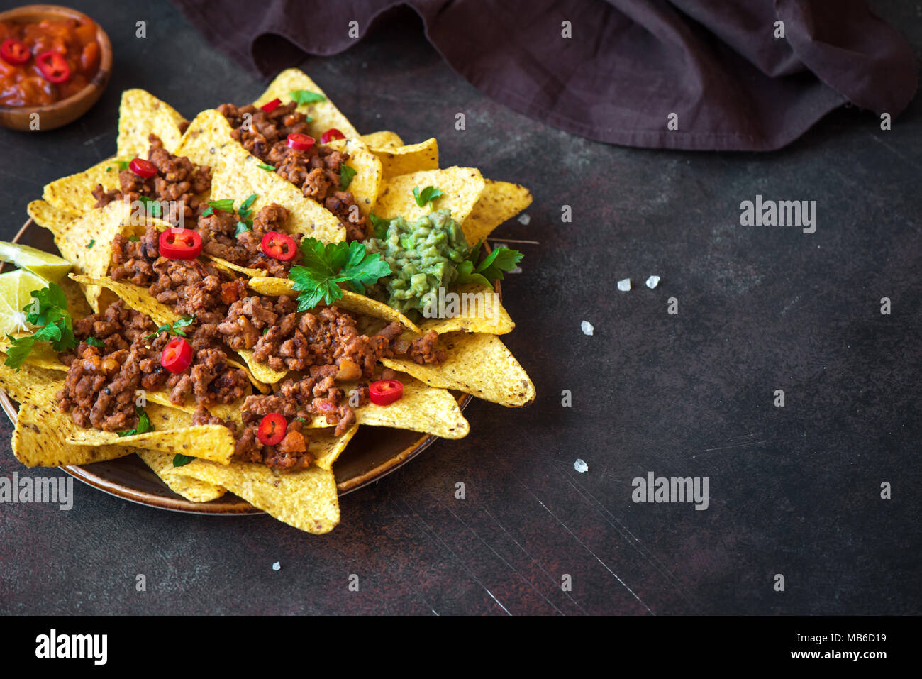 Mexican nacho corn tortilla chips with cheese, meat, guacamole and red