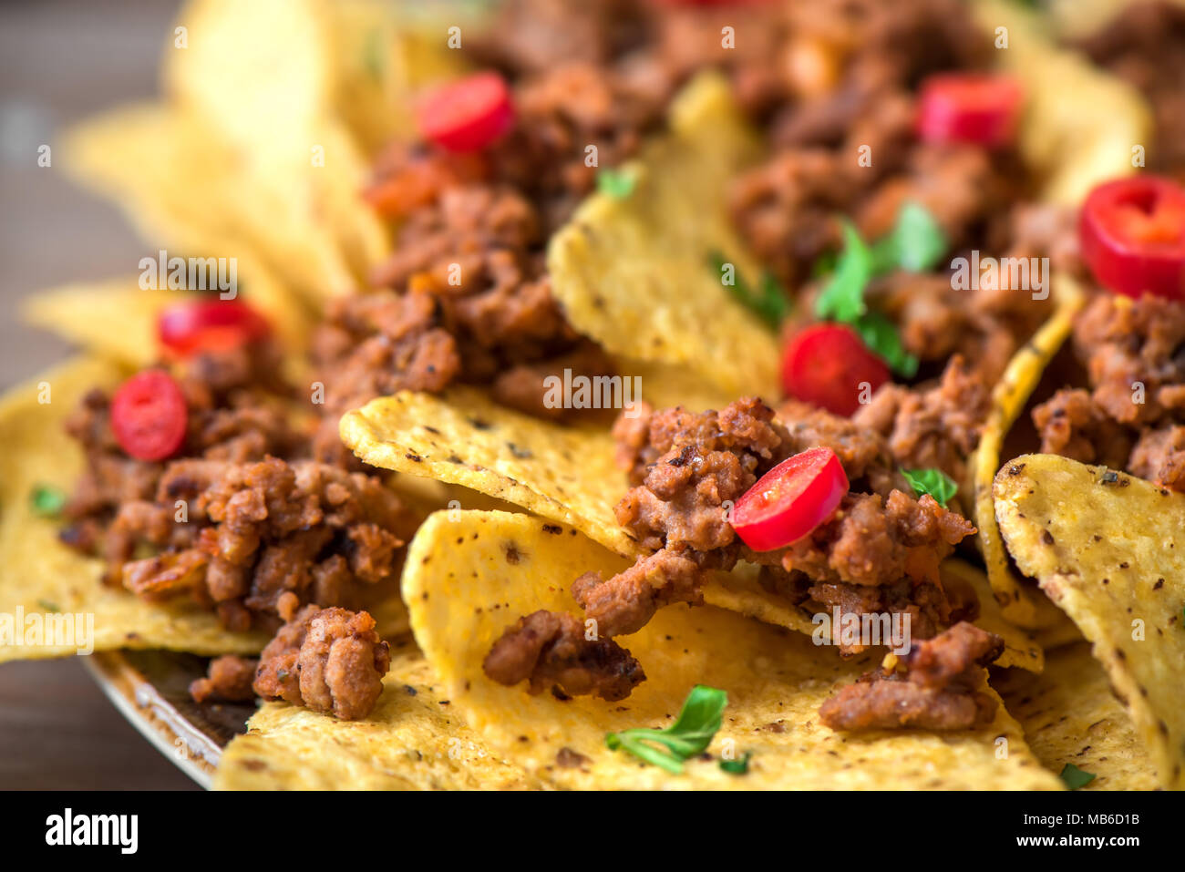 Mexican nacho corn tortilla chips with cheese, meat, guacamole and red hot spicy salsa. Nachos