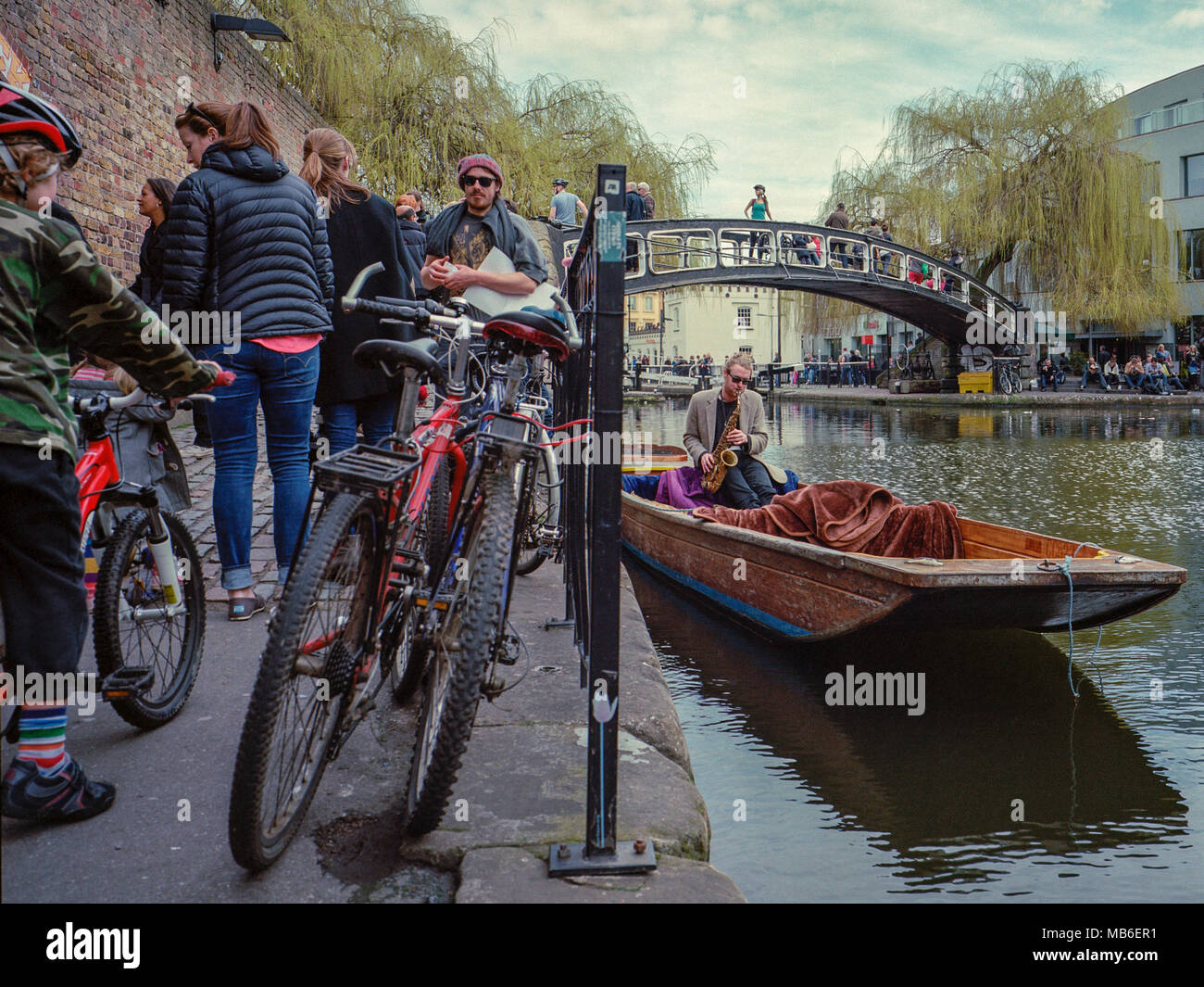 Camden Lock, Regent's Canal, near the famous London market, a busker plays the saxophone on a punt in this popular tourist spot. Stock Photo