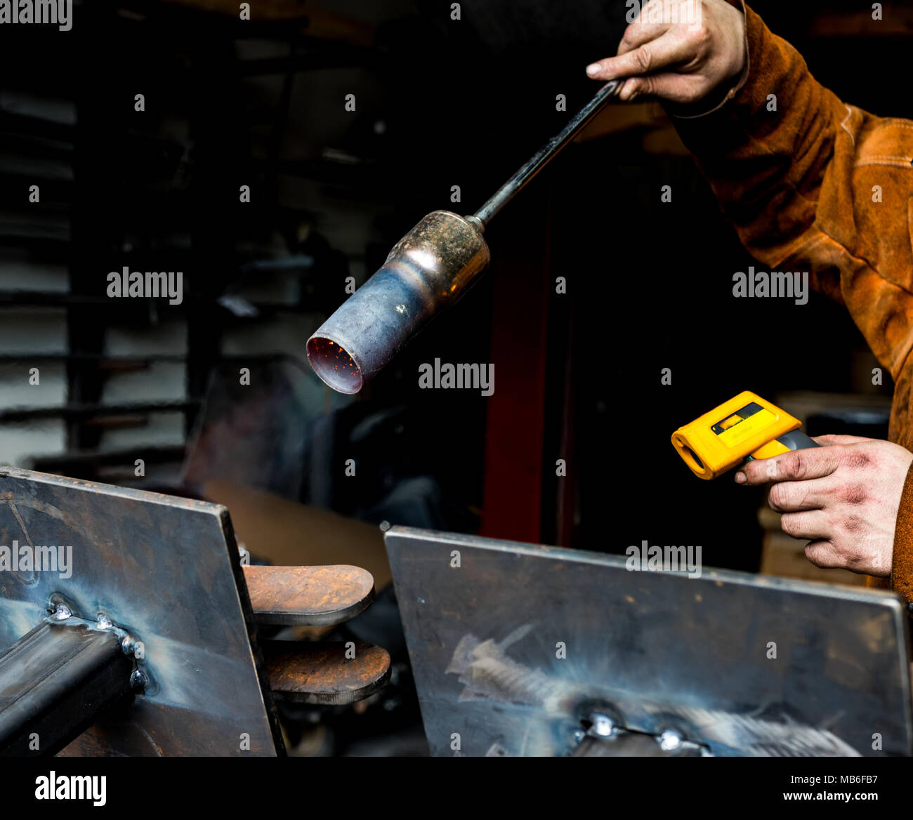 Metal worker preheating steel plates with a propane torch in preparation for welding and heat