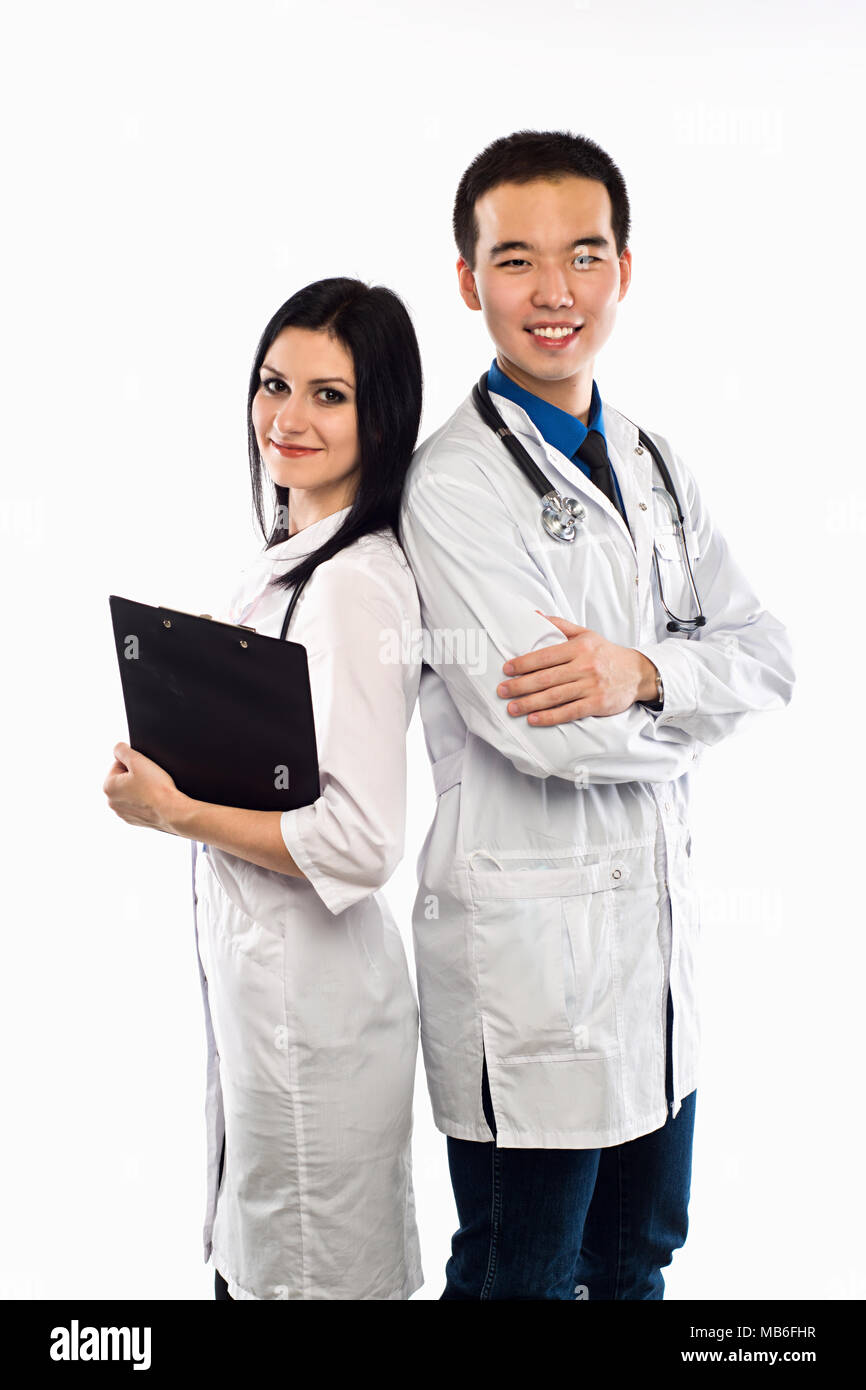 Asian doctor with a smiling happy Caucasian nurse or medical colleague standing back to back with folded arms isolated on white, upper body portrait c Stock Photo