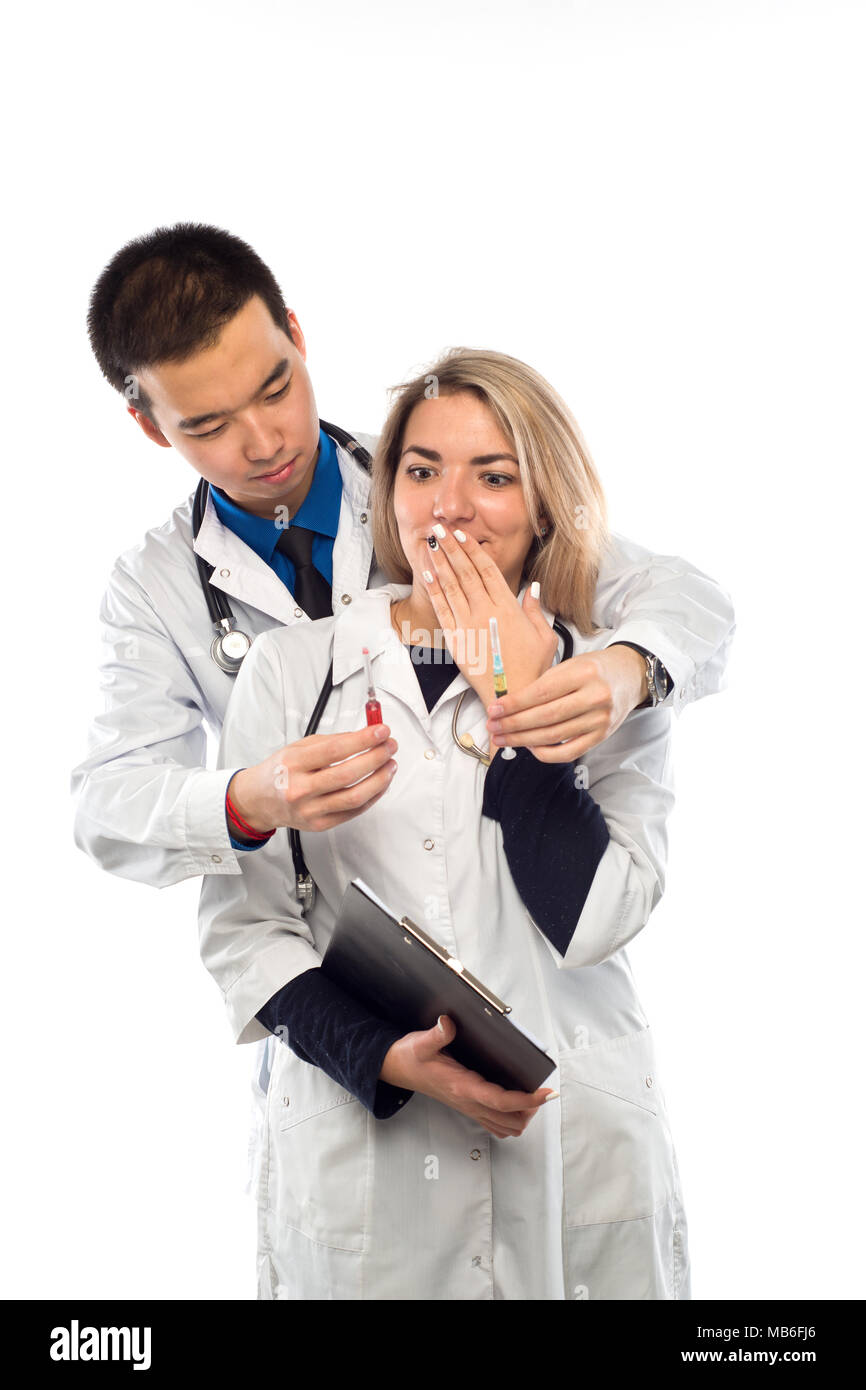 Doctor man stands behind a woman doctor offers to choose one of two syringes for injection Stock Photo