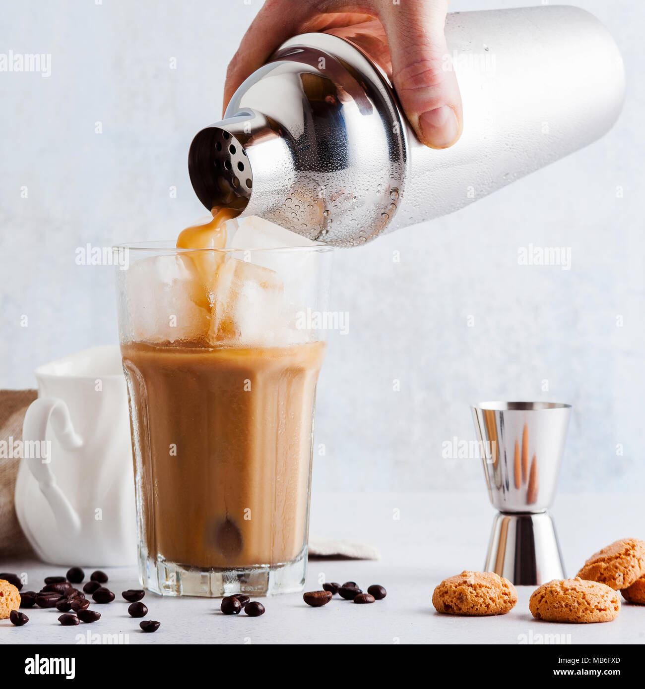 https://c8.alamy.com/comp/MB6FXD/pour-the-frappe-from-the-shaker-into-a-tall-glass-beautiful-and-clean-composition-with-coffee-beans-and-amaretti-biscuits-MB6FXD.jpg