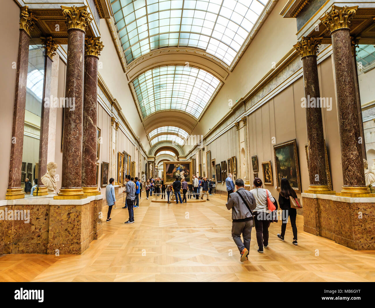 Louvre Museum paintings hall and visitors watching it. Paris. France Stock Photo