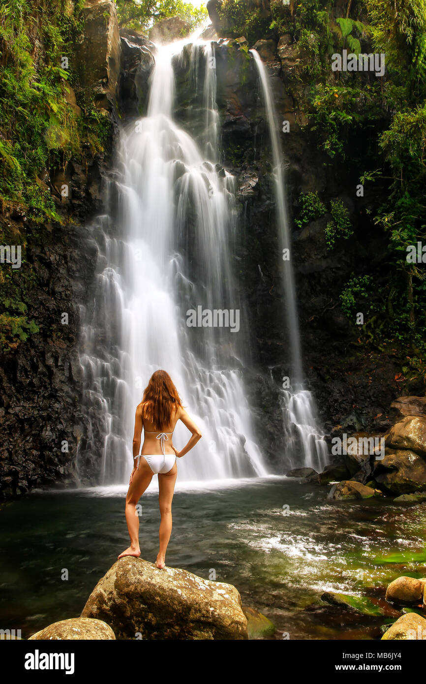 Young woman in bikini standing by Middle Tavoro Waterfalls in Bouma National Heritage Park on Taveuni Island, Fiji. Taveuni is the third largest islan Stock Photo
