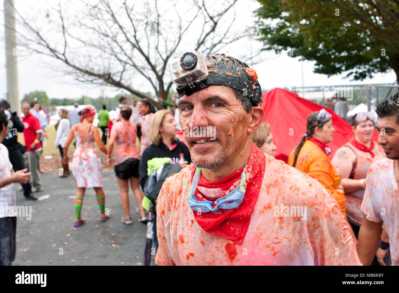 A man wearing a Go Pro camera on his head, is covered in pieces of tomato after participating in the Tomato Royale on October 19, 2013 in Conyers, GA. Stock Photo