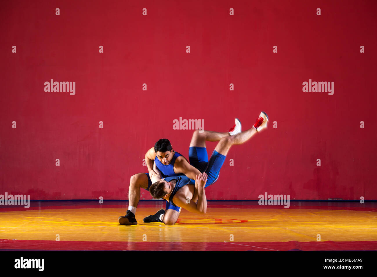 Two strong wrestlers in blue wrestling tights are wrestlng and making a