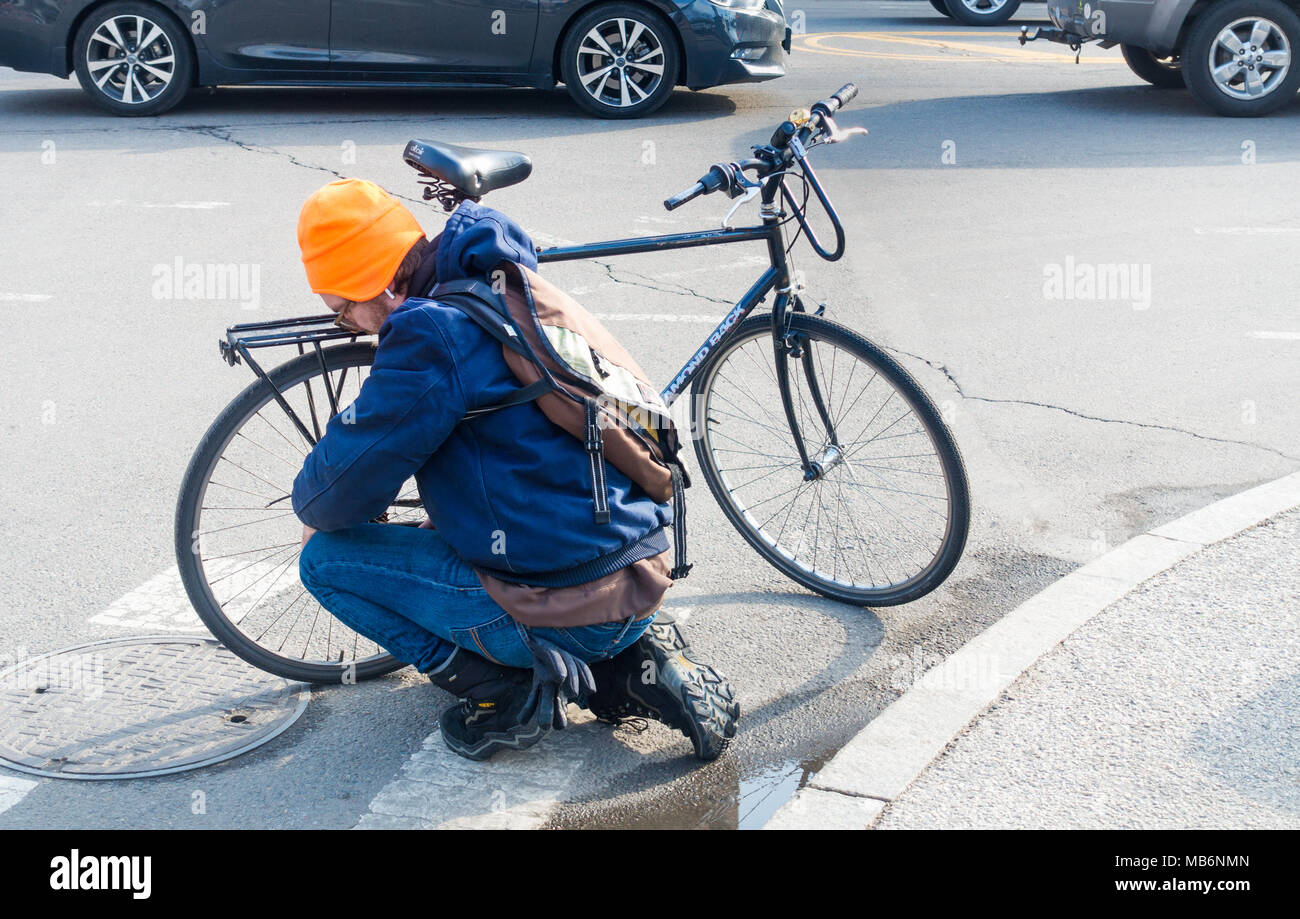 Early morning bicycle  commuter fixing a problem with the bike's back wheel in NYC Stock Photo