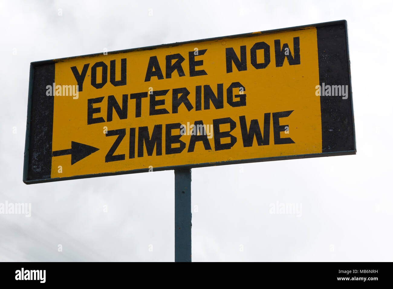 Sign marking the border on the Victoria Falls, Zimbabwe. The bridge connects Zambia and Zimbabwe over the River Zambezi. Stock Photo
