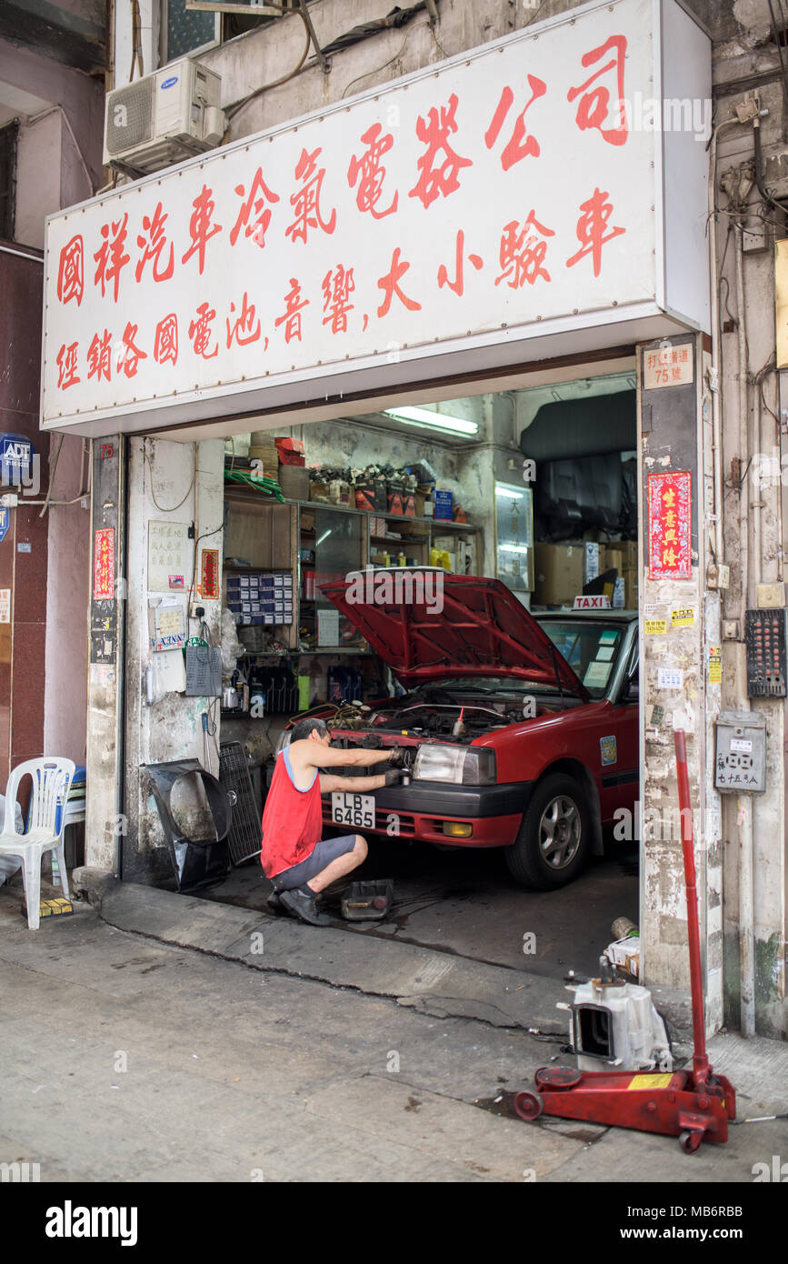 Man fixing a car in a car shop on the streets of Hong Kong Stock Photo