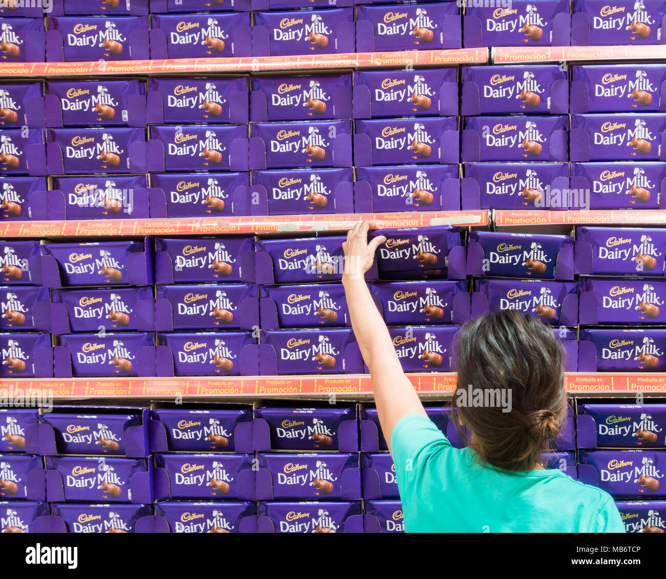 woman selecting Cadbury milk chocolate bar from supermarket display. Stock Photo