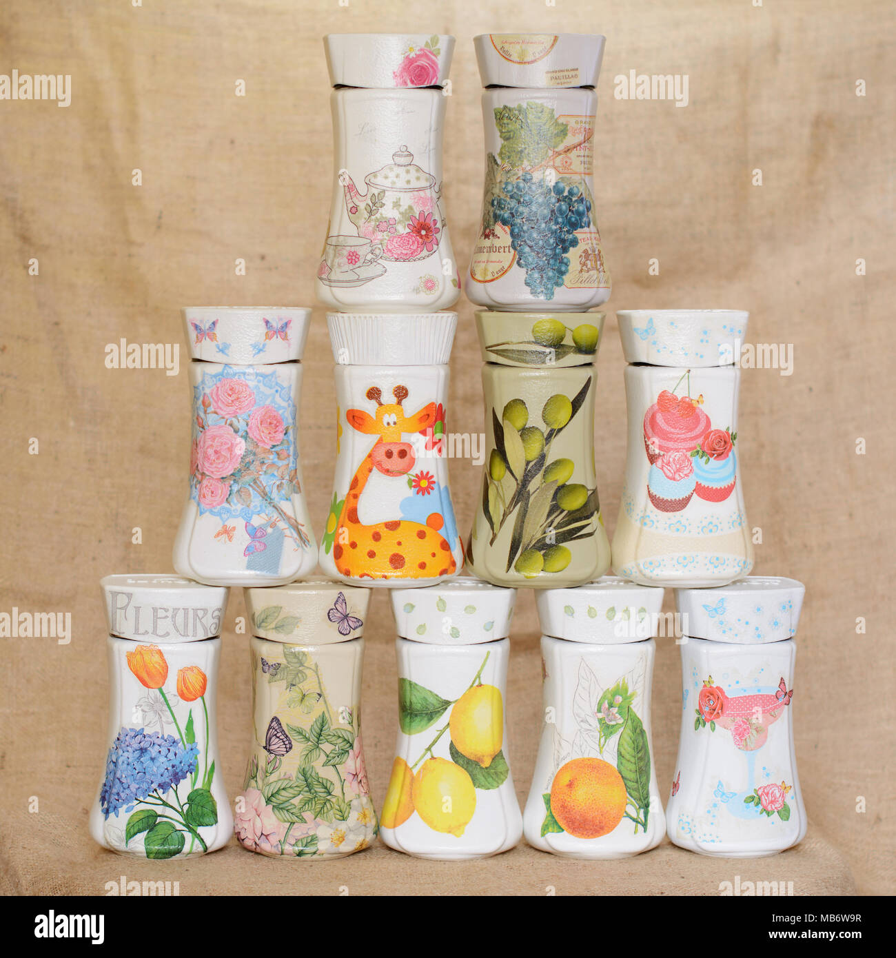 Decoupaged jars arranged in a triangular manner. Jars have different decorative motifs. One of the jars has written on it word Flowers in French. Stock Photo