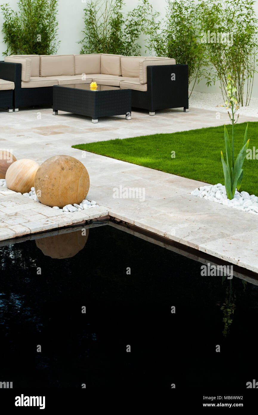 Minimalist & contemporary, 'Breathe' show garden with stylish patio, seating area, pond & stone spheres - RHS Flower Show, Tatton Park,  England, UK. Stock Photo