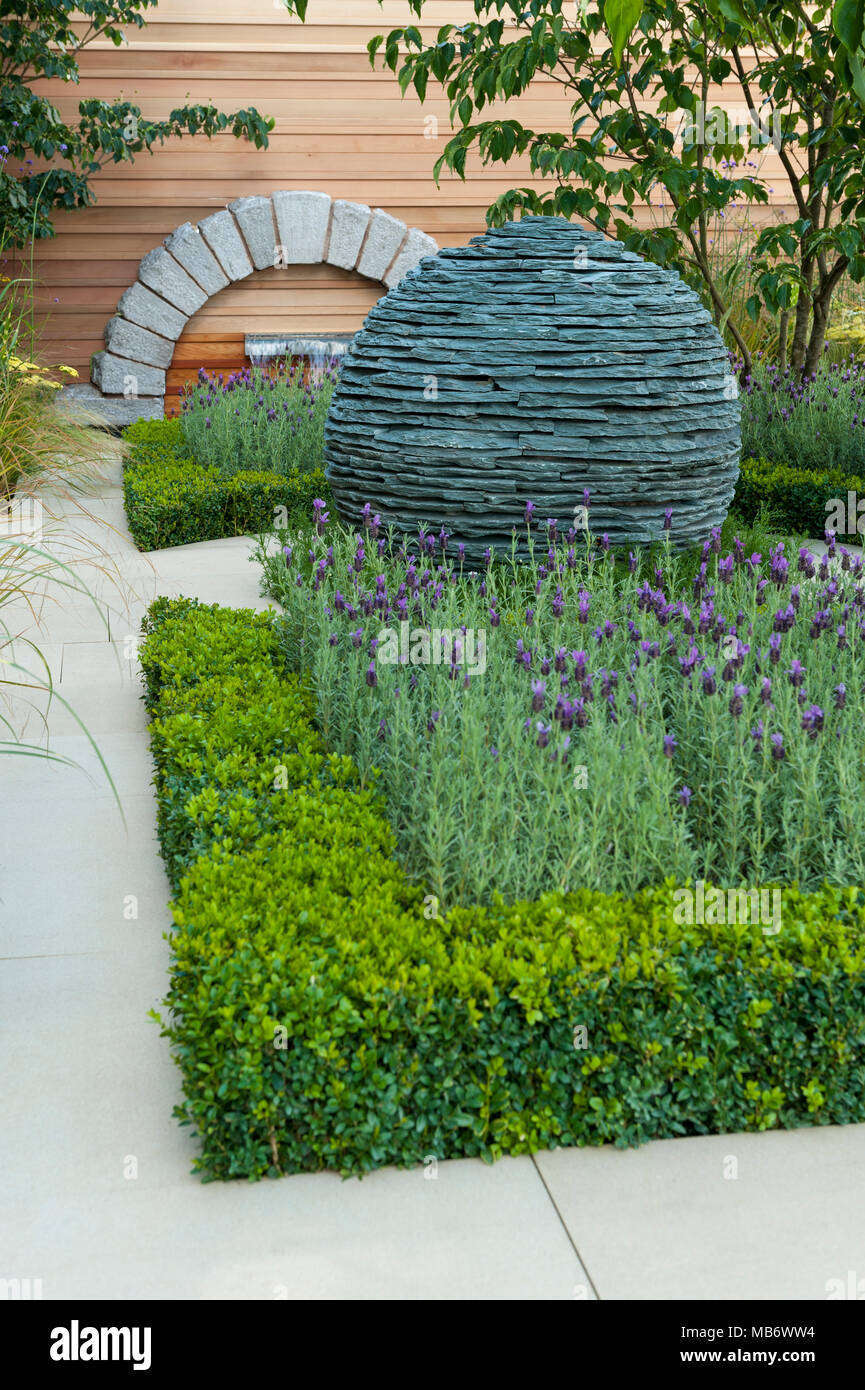 Original spherical stone centrepiece sculpture, path & medicinal plants - 'Embracing Tranquility' garden, RHS Flower Show, Tatton Park,  England, UK. Stock Photo