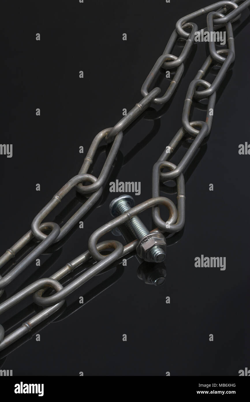 Metal chains threaded with nut and bolt as metaphor for