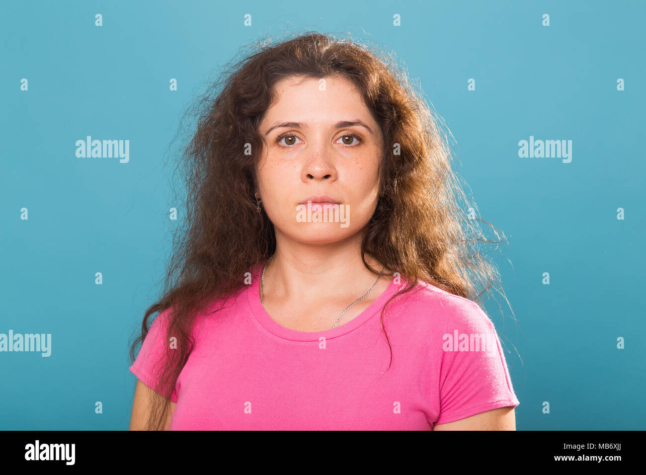 Close up portrait of a beautiful young woman with curly hair on blue ...