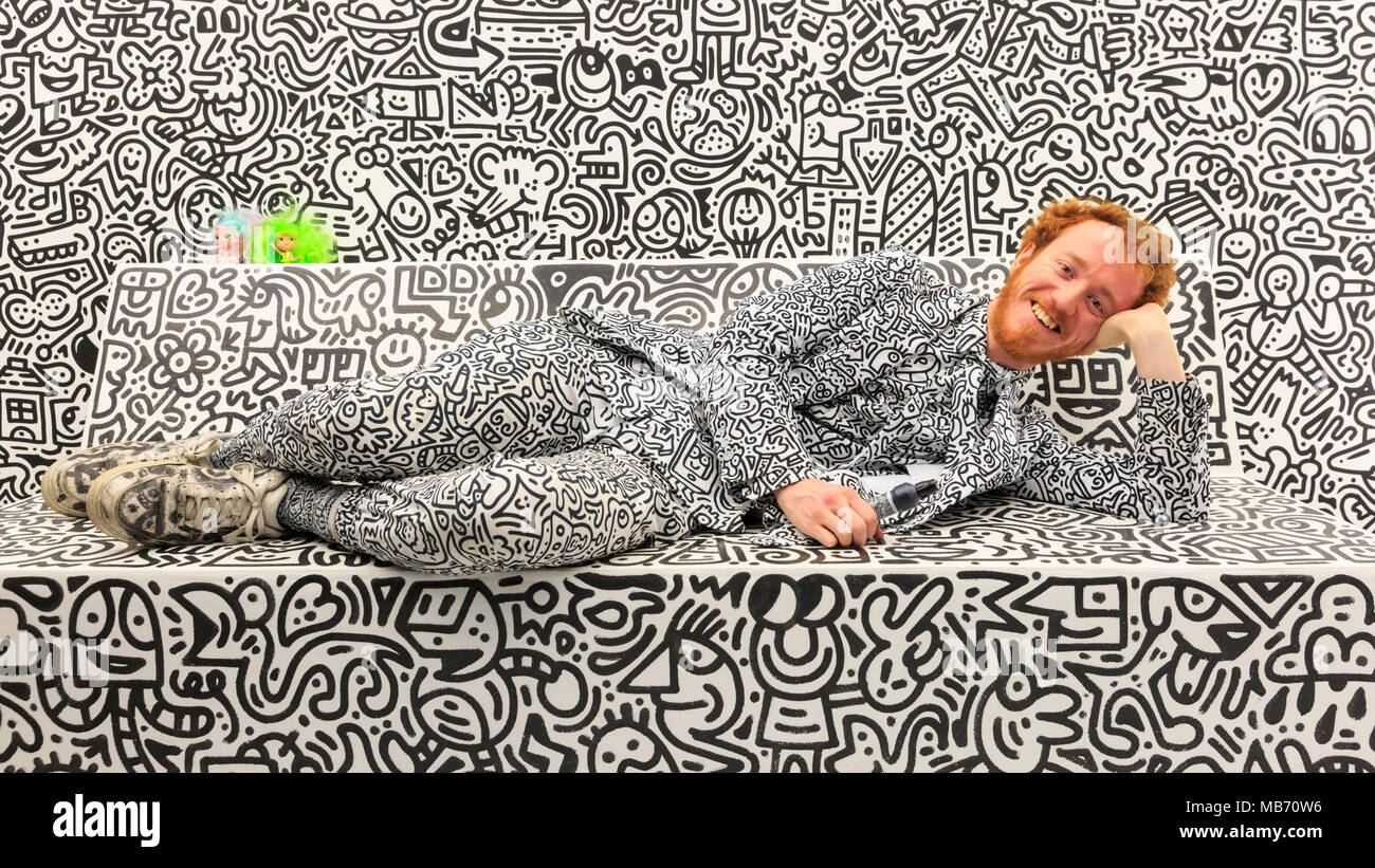 Exchange Square, London, 7th April 2018. Artist Sam Cox, portrait, known as 'Mr. Doodle', smiling. Mr Doodle, poses with his doodles artwork in 'The Doodle Room'. Visitors and art lovers have fun exploring the 'Sense Of Space' art exhibition and installations in Exchange Square, Broadgate, London, England, running until 18th May. Sense Of Space has four rooms overall, designed to activate the different senses. Credit: Imageplotter Stock Photo