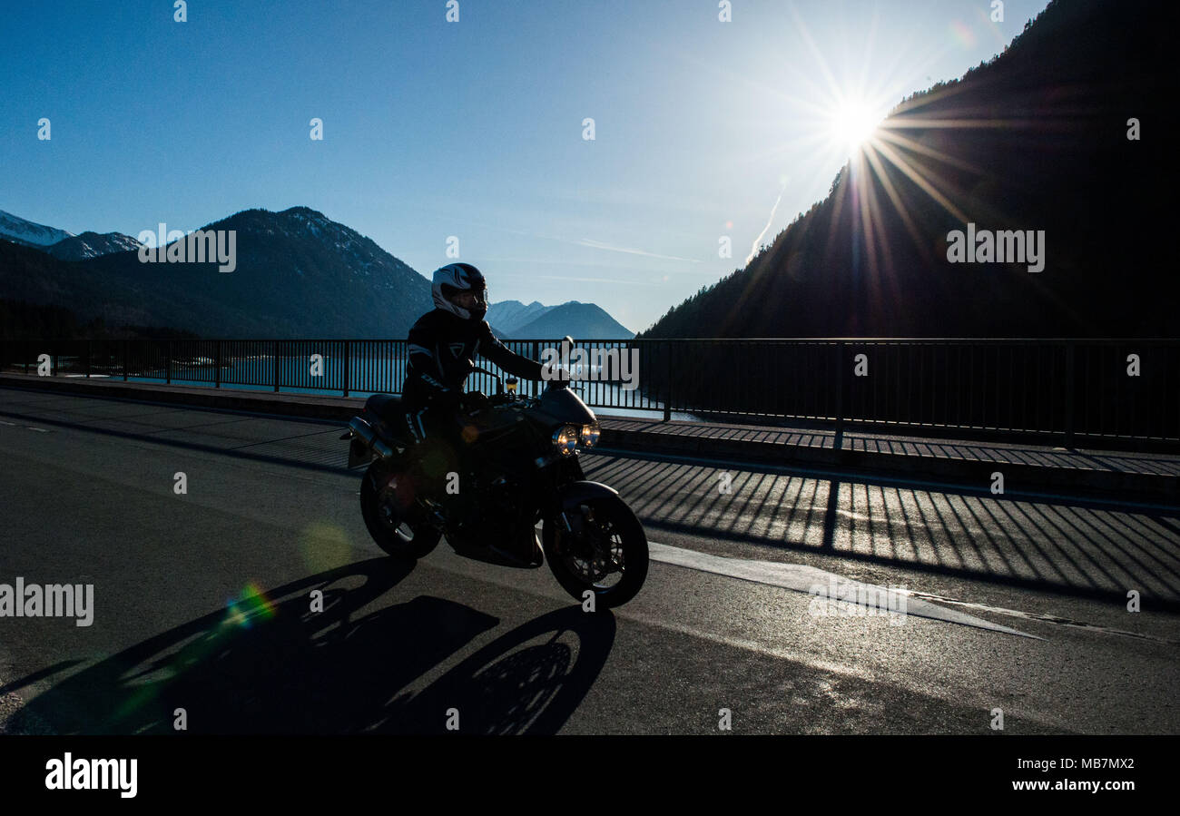07 April 2018, Germany, Lenngries: A man and a woman motorbiking in summer-like weather along the Sylvenstein lake. Photo: Lino Mirgeler/dpa Stock Photo