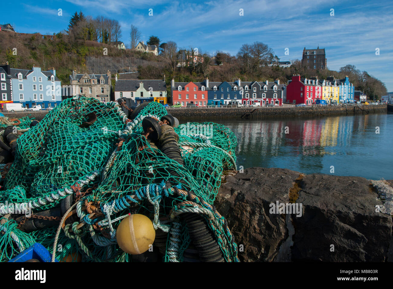 Fishing nets on the seafront of Tobermory with the brightly coloured shops, houses and hotels on the seafront Stock Photo