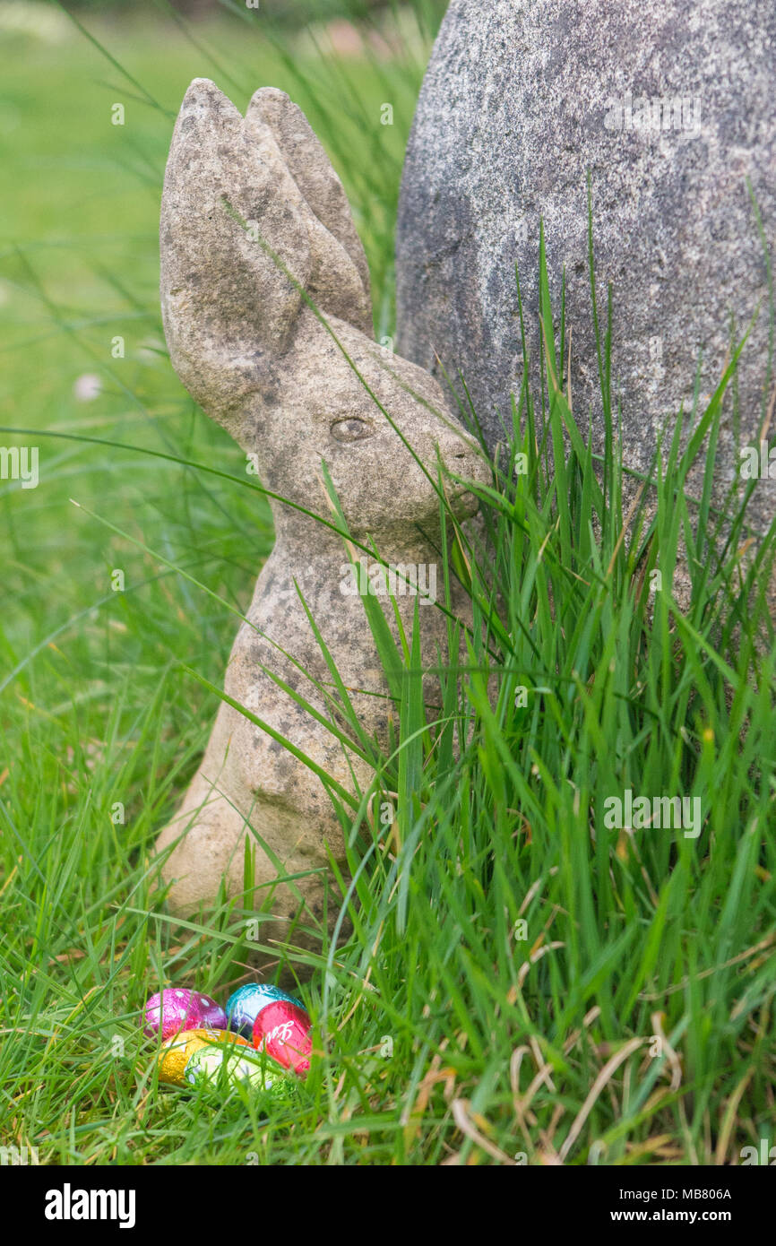 A stone rabbit and chocolate eggs in brightly coloured foil Stock Photo