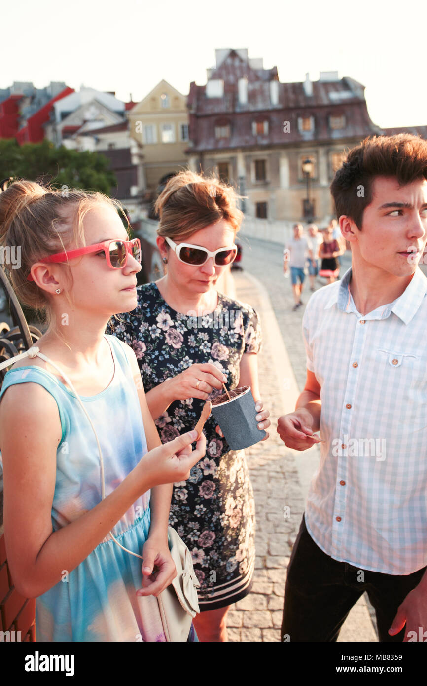 Family spending time together in the city centre enjoy eating ice cream on a summer day. Mother, teenage girl and boy spending quality time Stock Photo