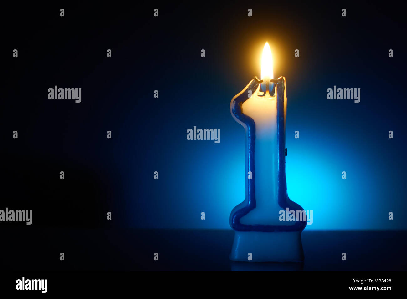 Number One - Burning birthday candle on blue background Stock Photo