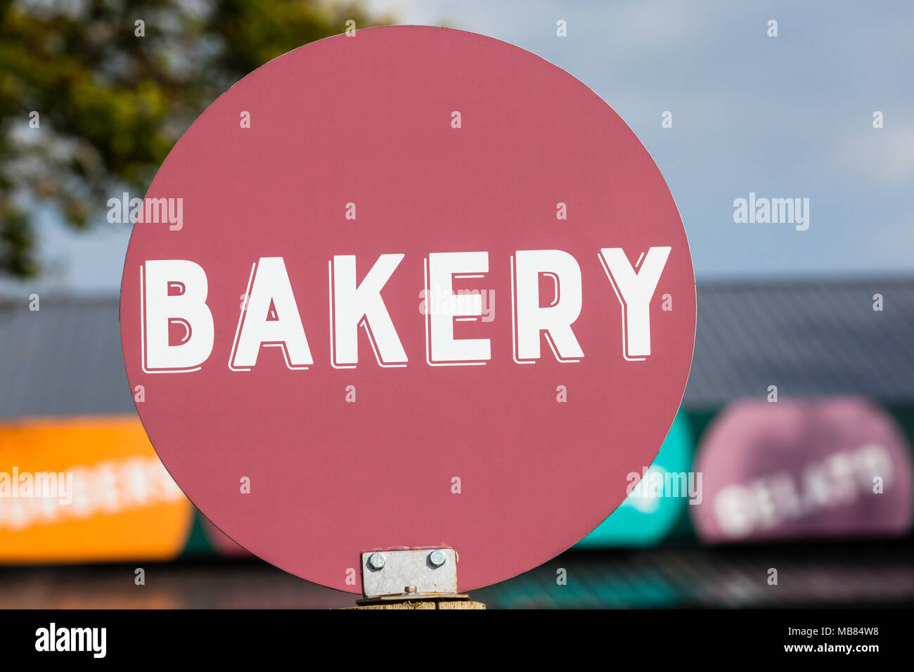 Bakery word white letters on maroon round disk sign board outside food store. Stock Photo