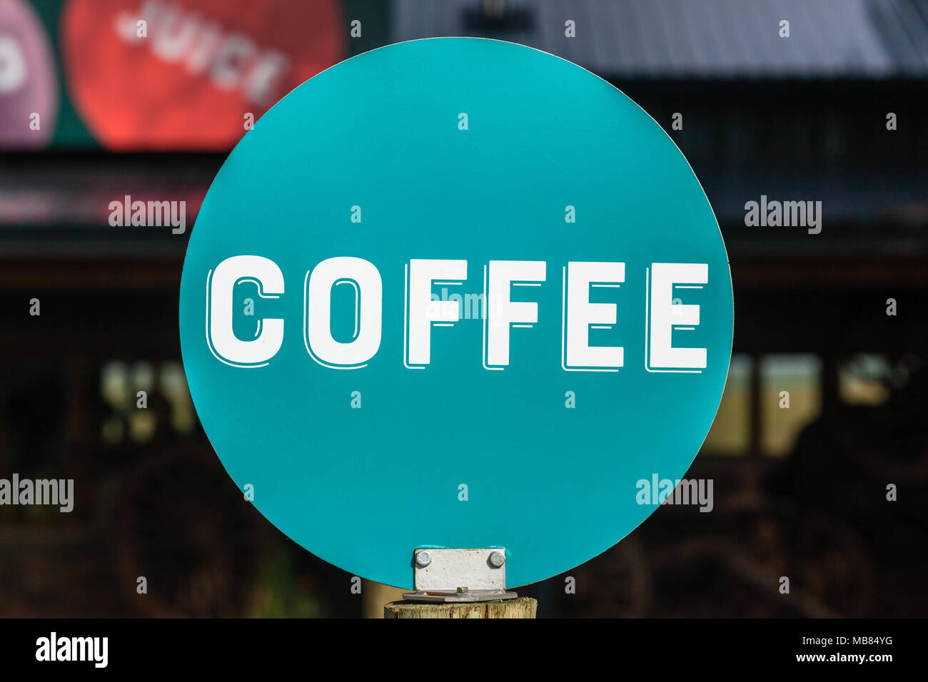 Coffee word white letters on round disk sign board outside food store. Stock Photo