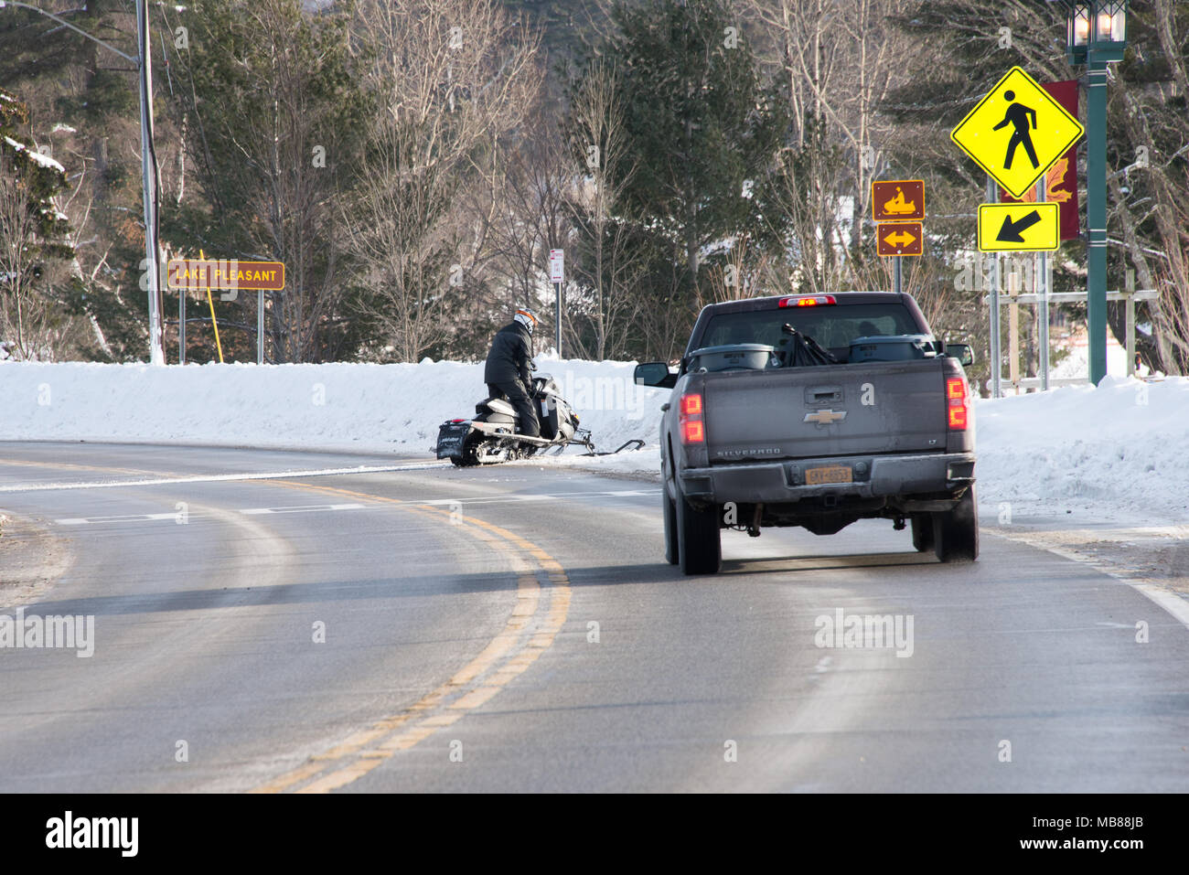 A snowmobile crossing the highway in Speculator, NY USA in front of a