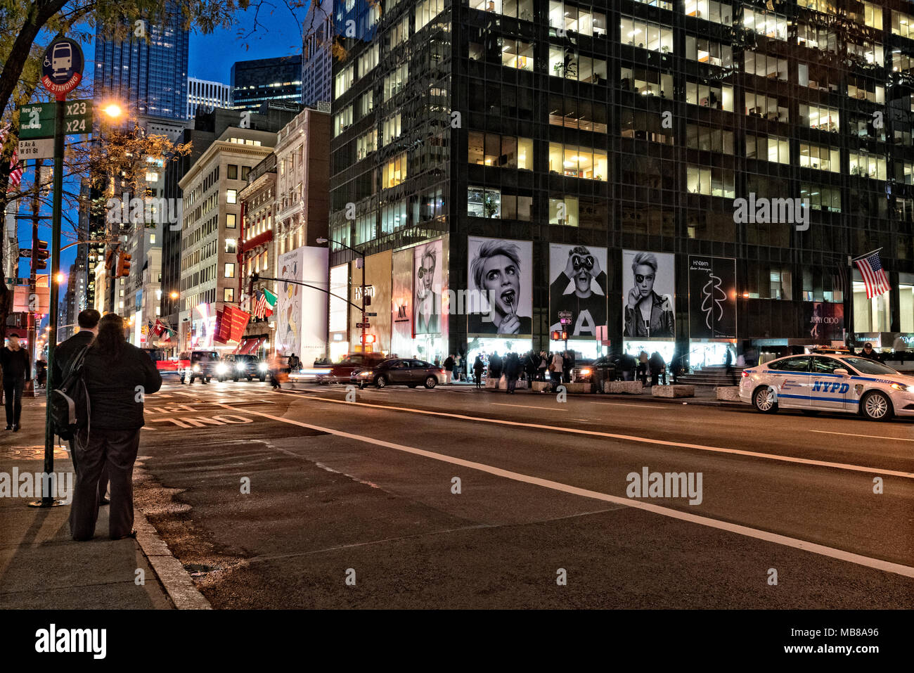 New York City, Manhattan, Fifth Avenue, Midtown.  Two People Waiting at A Bus Stop at Twilight. Stock Photo