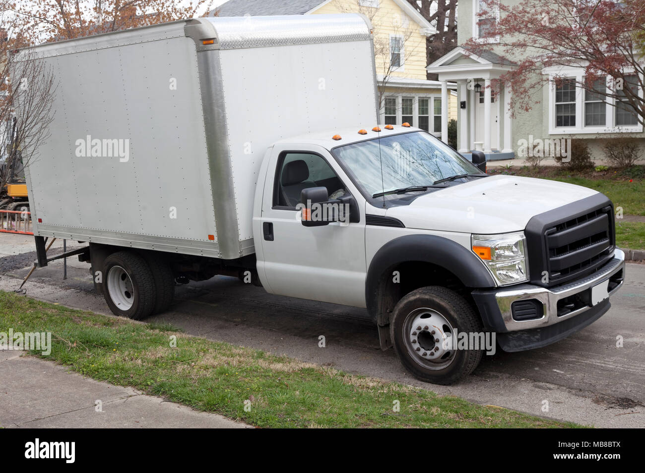 White delivery lorry van parked on residential neighborhood street. Stock Photo