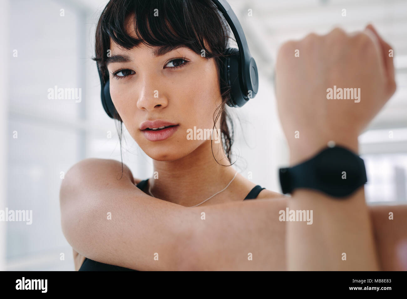 Close up of healthy woman with headphones doing arm stretching exercise. fitness woman stretching hands at health club. Stock Photo