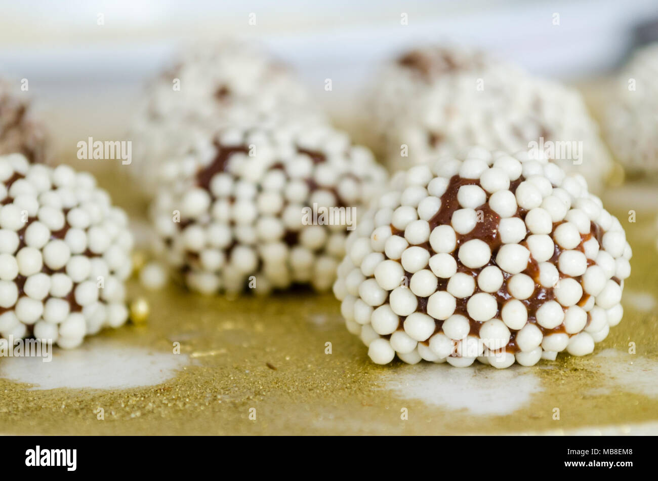 Brigadiers granulated with crunchy white balls on golden tray. Stock Photo