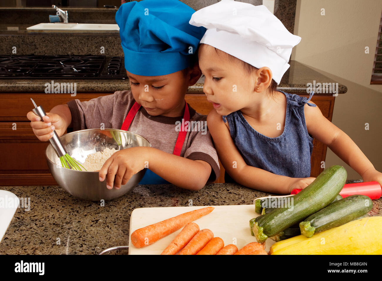 Siblings eating and cooking in the kitchen Stock Photo Alamy