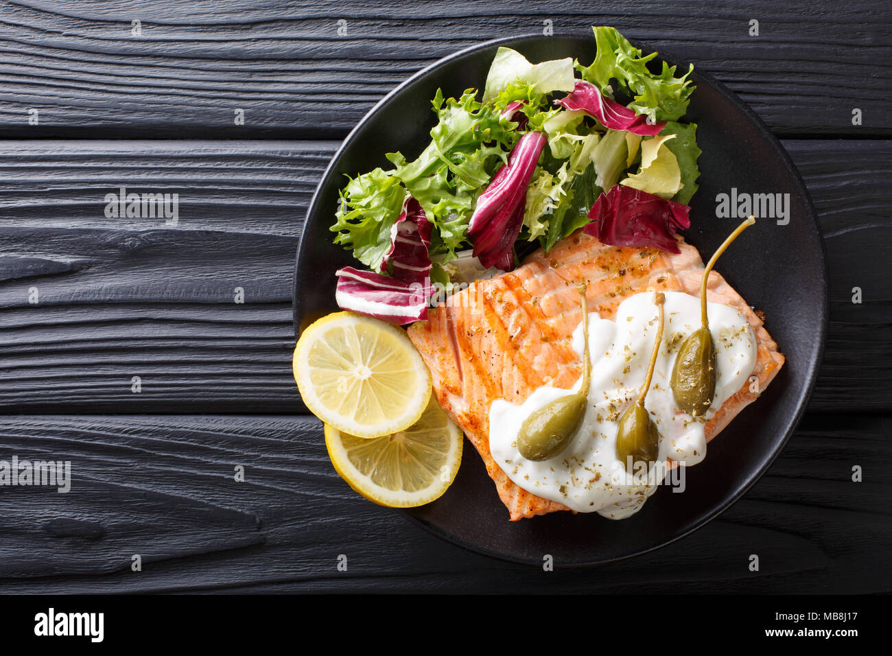 salmon piccata with capers and fresh mix salad closeup on a plate