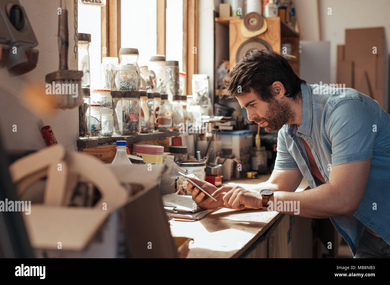Young woodworker using a tablet in his workshop Stock Photo