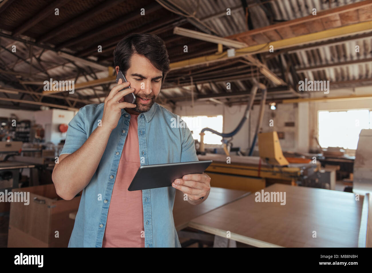 Woodworker talking on his cellphone and using a tablet Stock Photo
