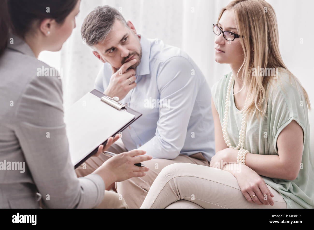 Upset young woman talking to a female psychologist, with her husband by