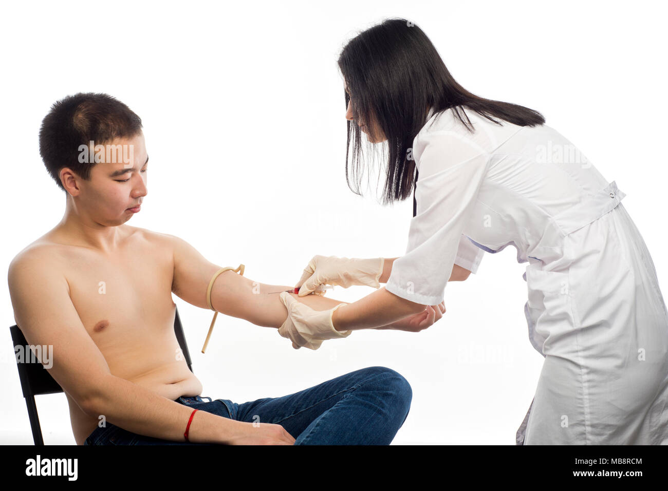 a female doctor injections into a vein or takes a blood test from the vein of the patient's hand of East Asian appearance. Stock Photo