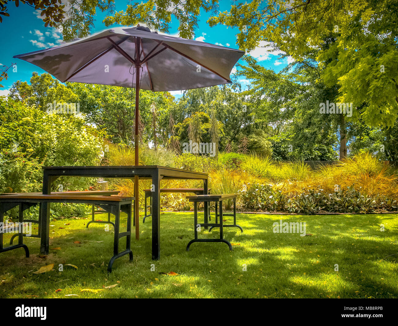 MARLBOROUGH, NEW ZEALAND - DECEMBER 6: Furniture Dining Table with Chairs and Parasol in the Shade in a Lush backyard Garden Stock Photo
