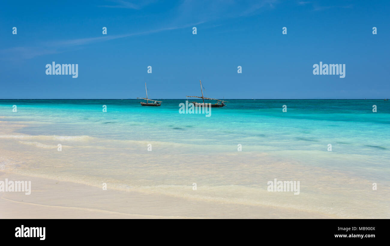 Zanzibar beach with white sand, waves and traditional fishing boats Stock Photo